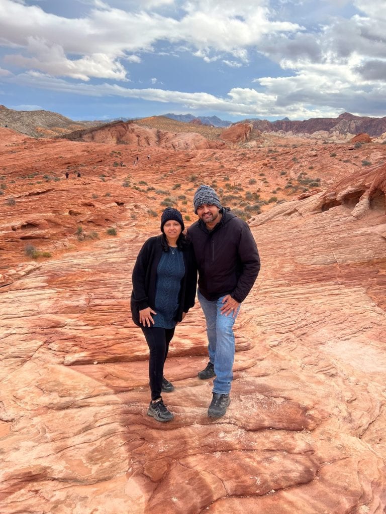 A couple posing on the rolling striped hills of fire wave trail in Valley of Fire State Park