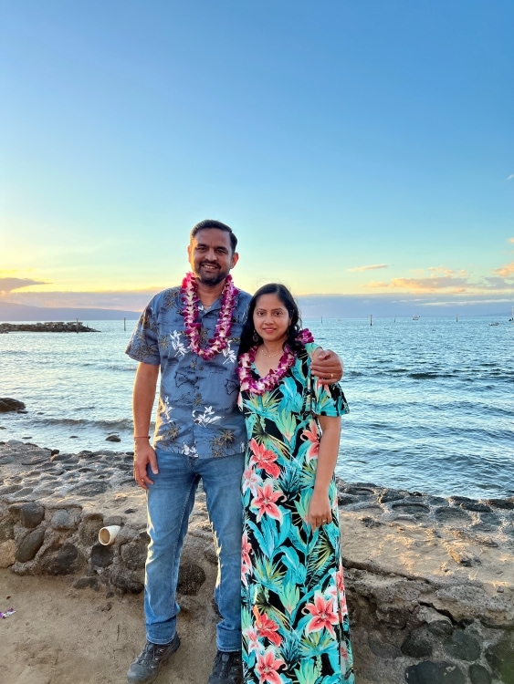 Couple standing against ocean backdrop with lei garlands