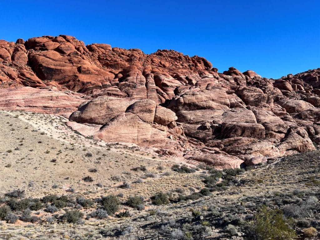 Hikers on the Calico Hills trail with red rock hills in the background