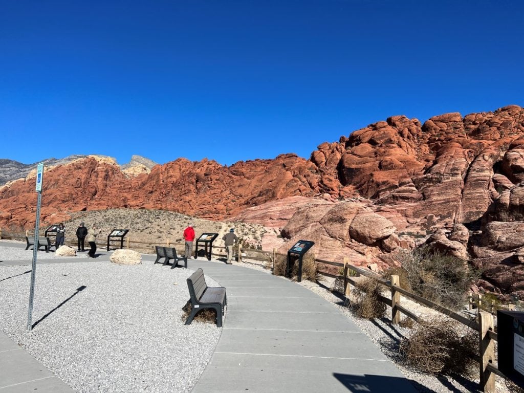 A paved observation area to view the red colored Calico Hills with benches and information boards.