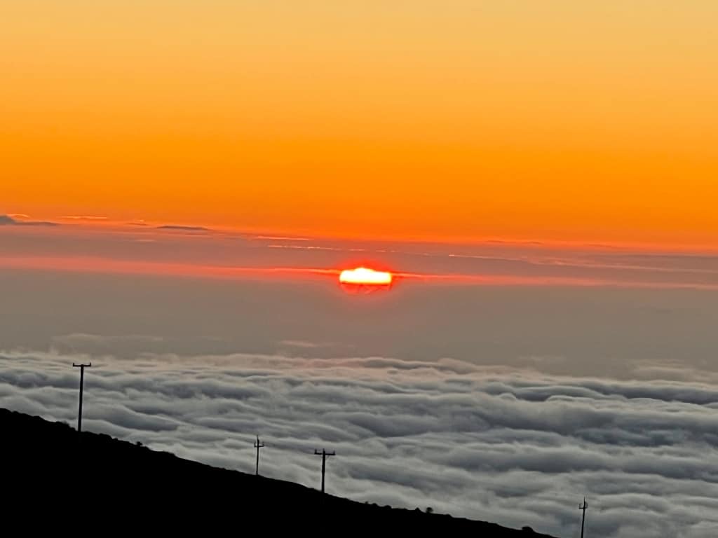 sun setting over the horizon over the clouds with orange colored skies