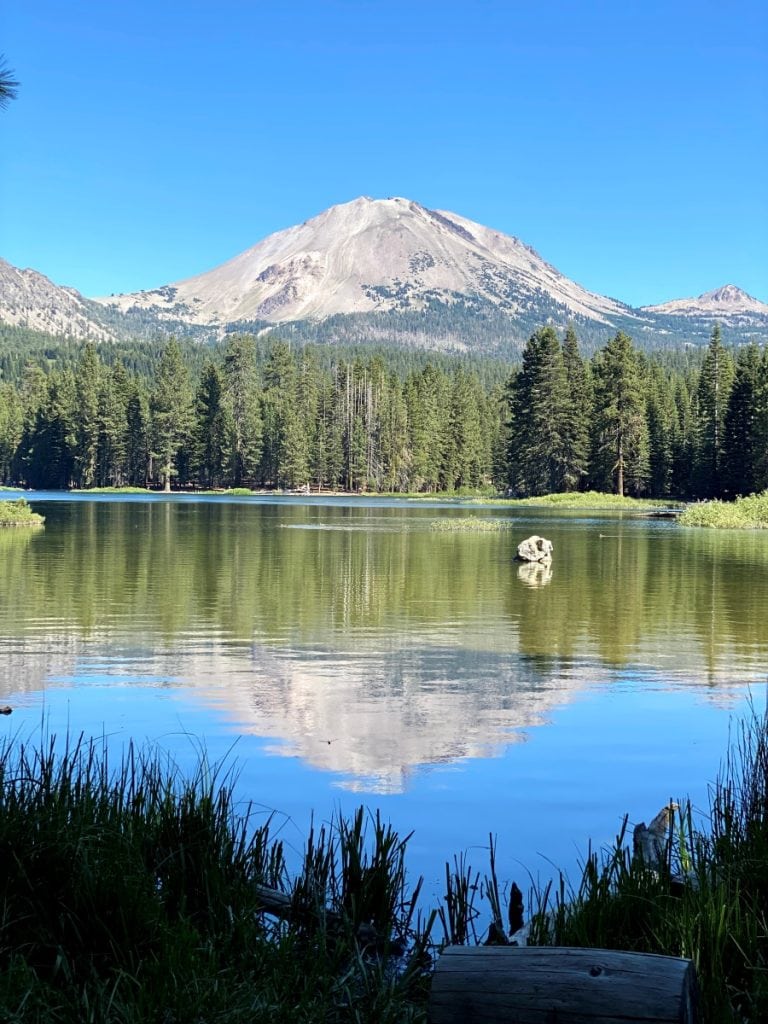 Lassen Peak and green trees reflecting in the clear water of a lake