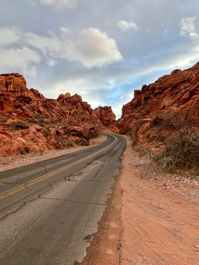 Stunning Mouse's Tank Road with fiery red rock cliffs on both sides of a winding road - in Valley of Fire State Park in Nevada.