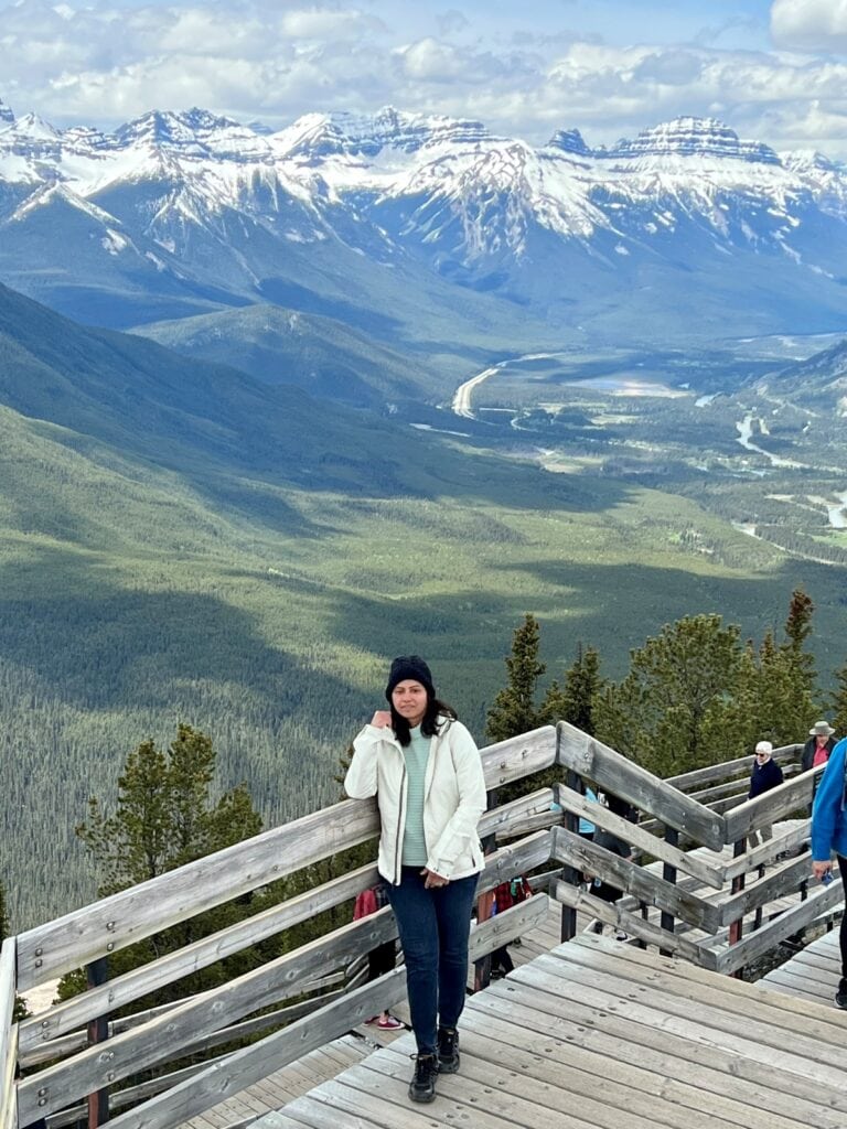 Anu posing on a boardwalk with Canadian Rockies behind her