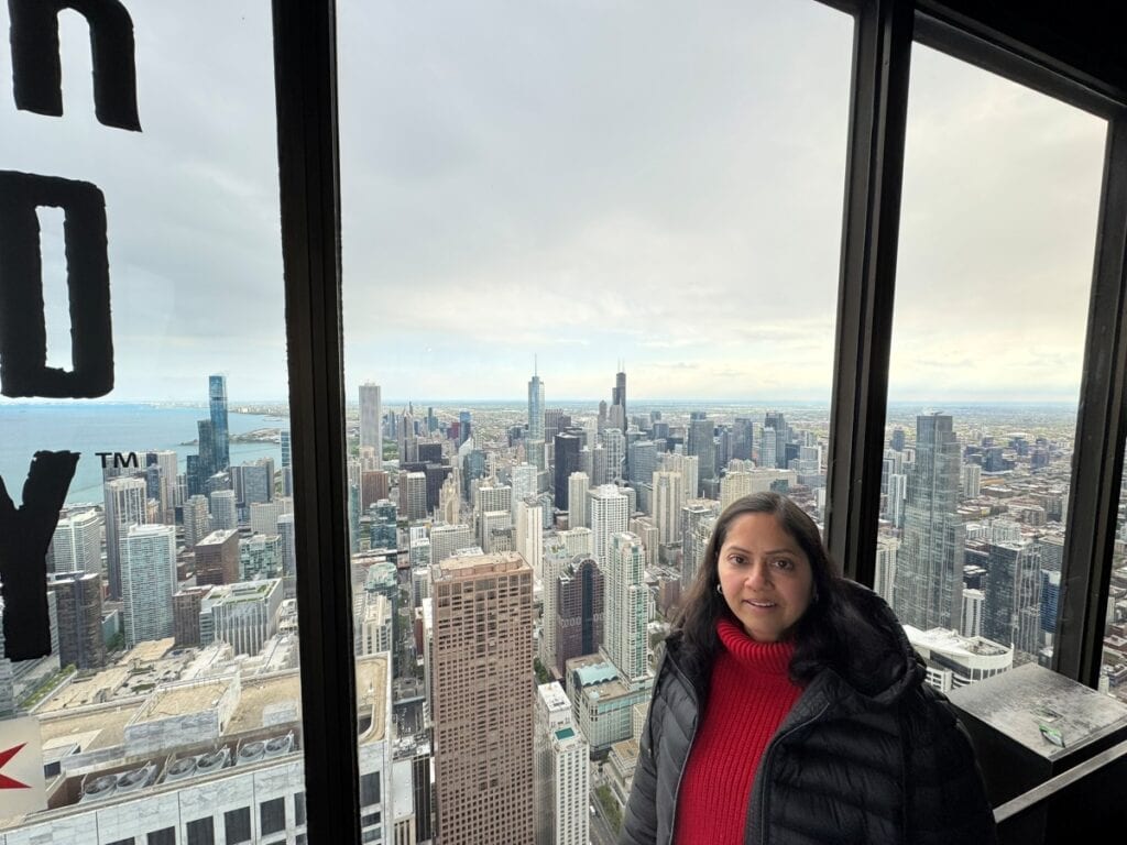 girl posing on Chicago 360 observation deck with downtown views in backdrop