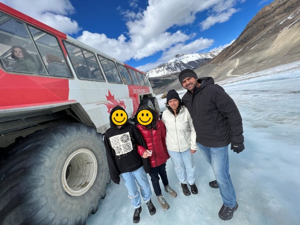 A family standing near an ice explorer vehicle on a glacier