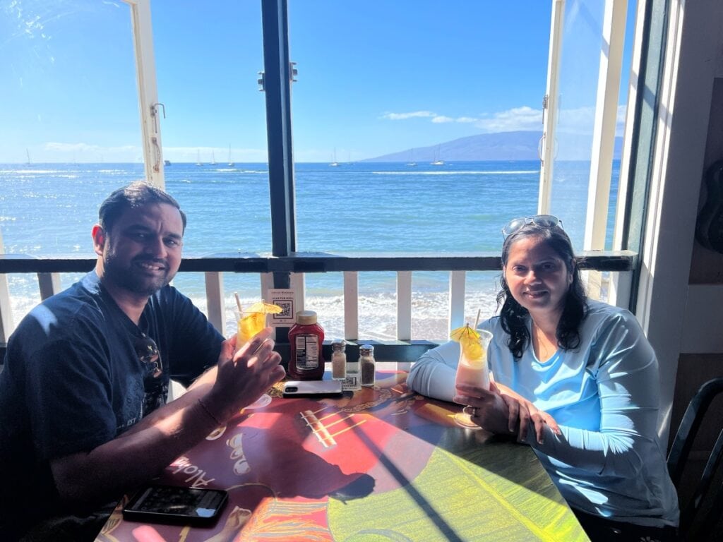 A couple sitting on a restaurant table next to a window with ocean views