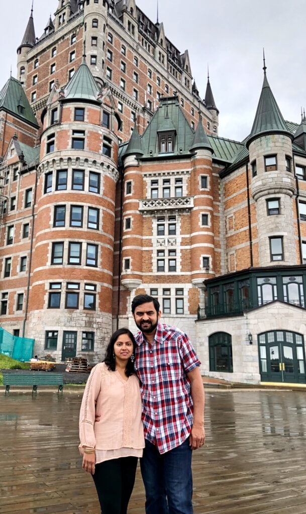 A couple posing in front of Fairmont Le Château Frontenac in Quebec City