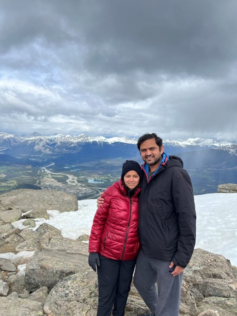 A couple posing on a mountain top with snow on the ground