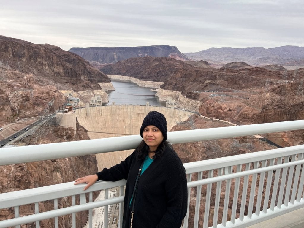 Girl standing against the railing on Memorial Bridge with vast Hoover dam and Lake Mead in the background. Visiting Hoover Dam from Las Vegas is an excellent outdoor excursion.