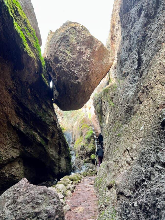 Huge boulder lodged between rocks and hiking trail on Bear Gulch Cave Trail in Pinnacles National Park