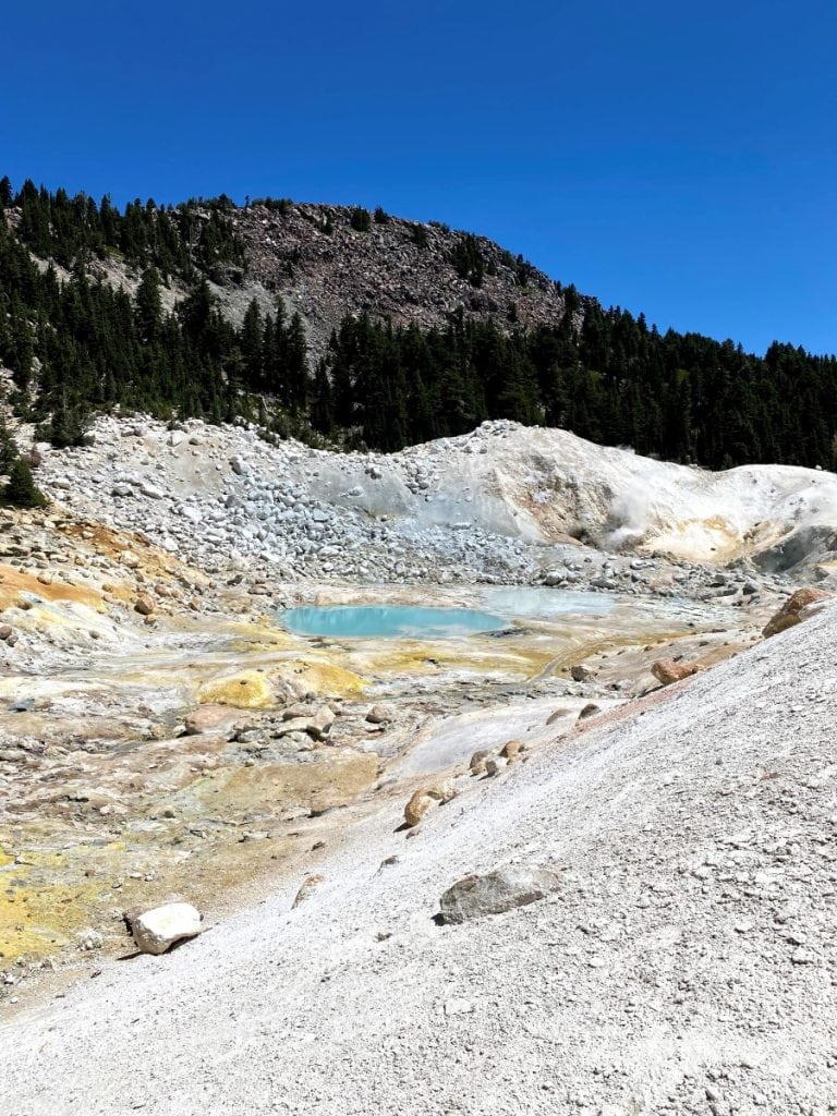 Bumpass Hell area with different colors in landscape like yellows and greens and a small blue water body