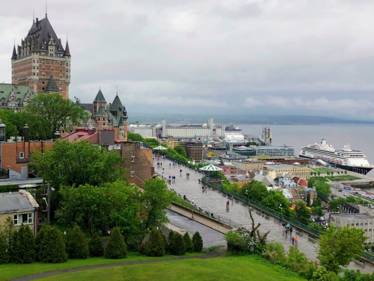 Fairmont Le Château Frontenac overlooking Dufferin Terrace and the St Lawrence River with a cruise ship docked in Quebec City.