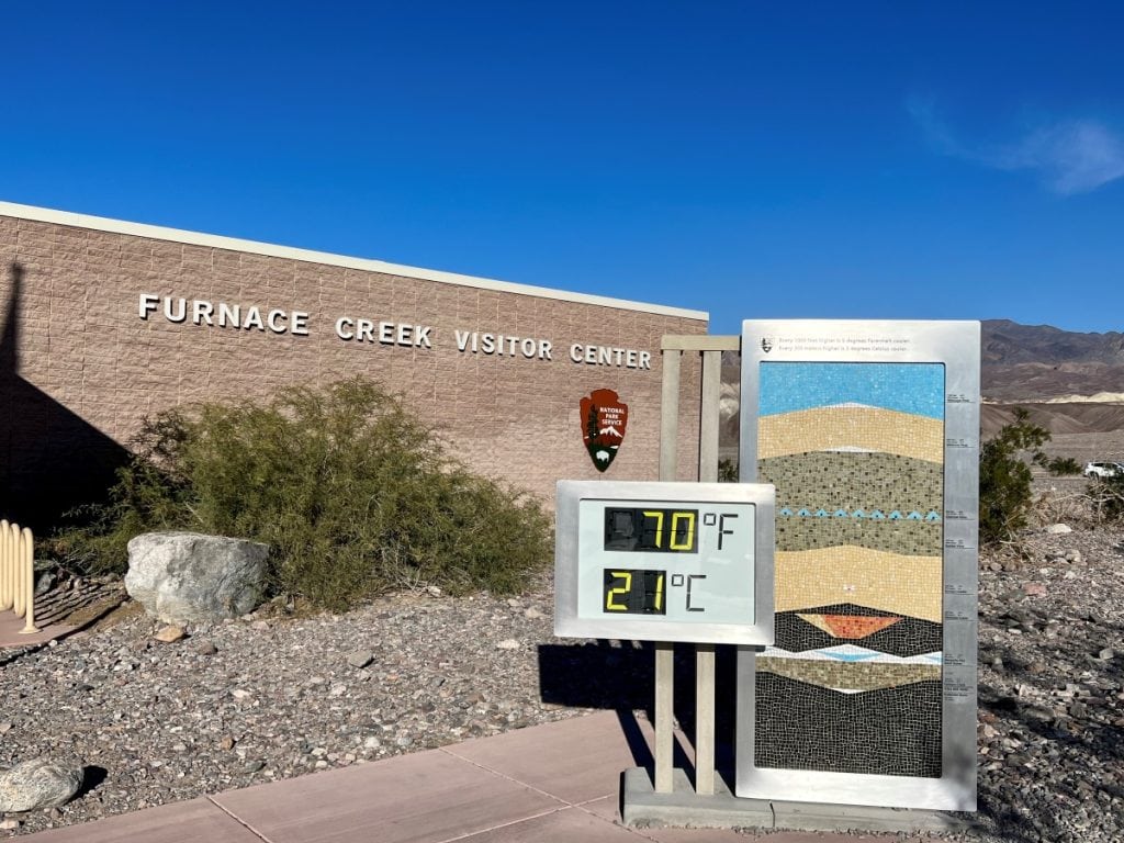 Furnace Creek Visitor Center building with a sign outside that shows the current temperate in Celsius and Fahrenheit. 