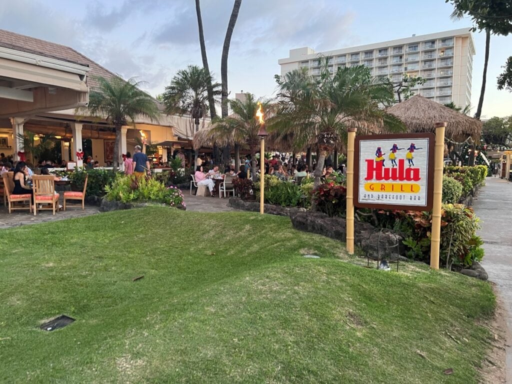 Open air restaurant with a board outside that reads Hula Grill