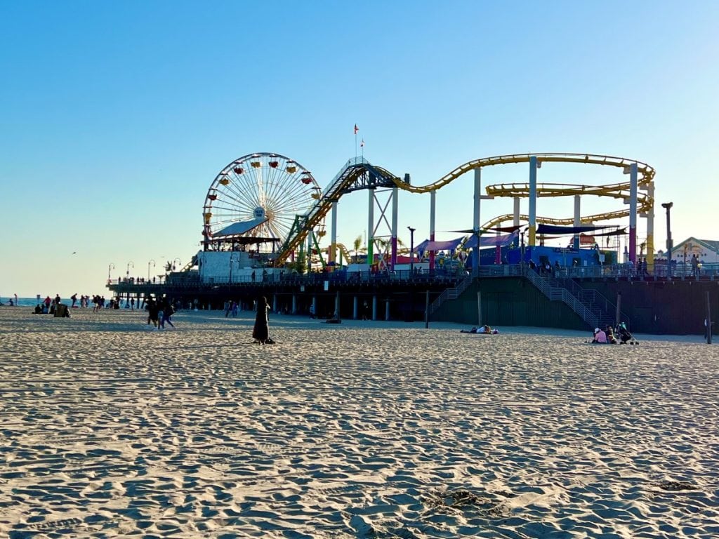 Pier with Ferris wheel and rides above a sandy beach in Santa Monica whic his one of the best beaches in Los Angeles for families